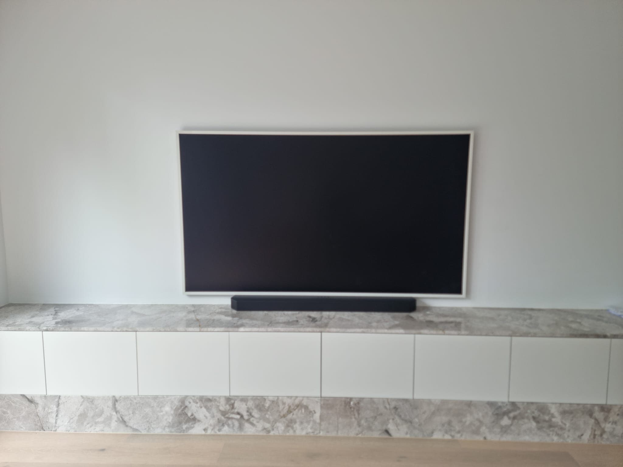 Soundbar on a marble-topped white console under TV