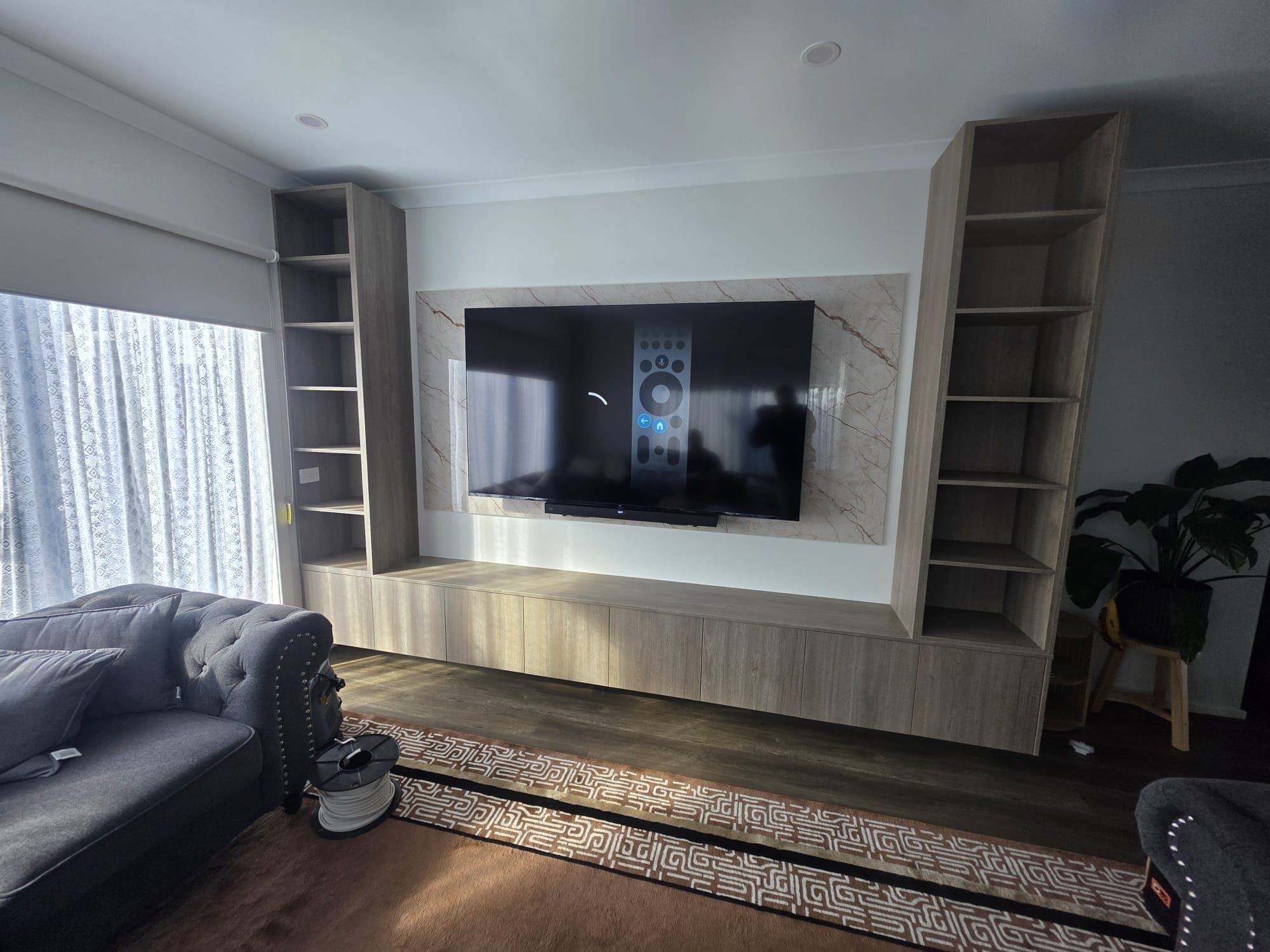 Custom entertainment wall with a mounted TV and on-screen remote from a Clear View job
