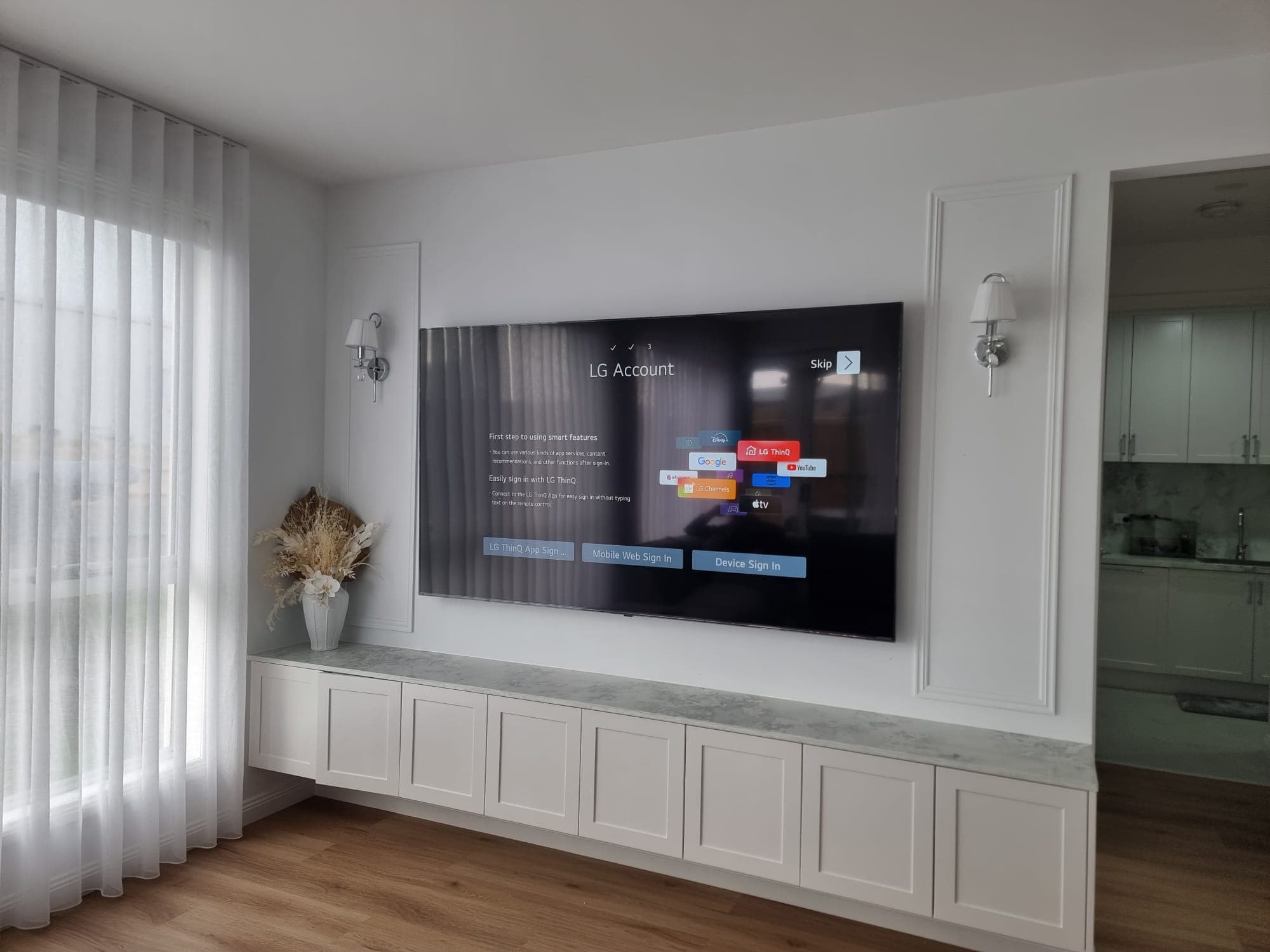 LG TV above marble console with wall sconces