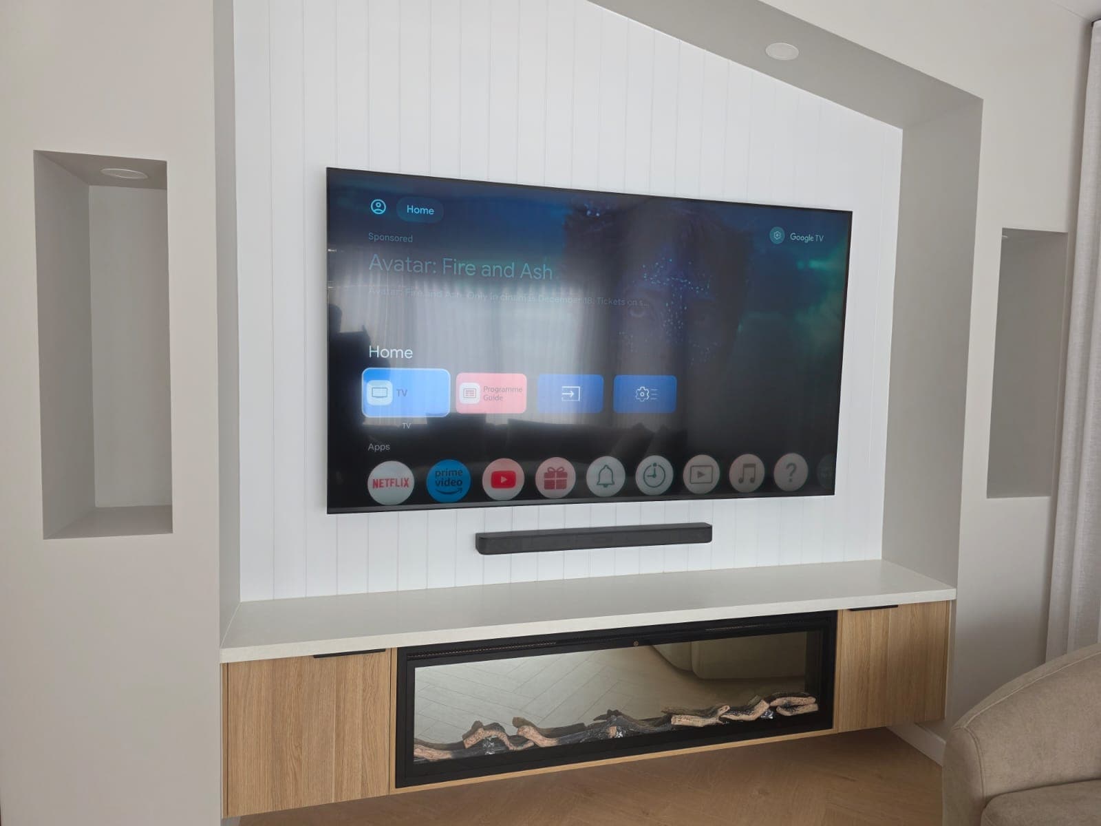 Google TV on a shiplap wall above a fireplace
