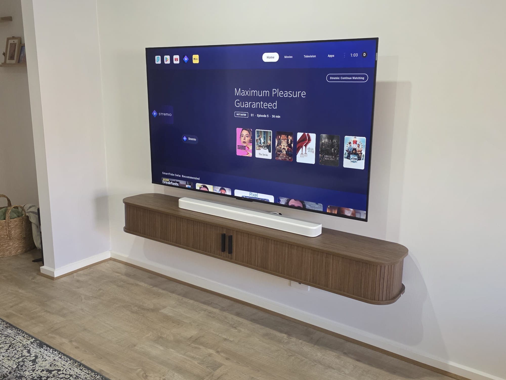 Wall-mounted TV with white soundbar and streaming apps