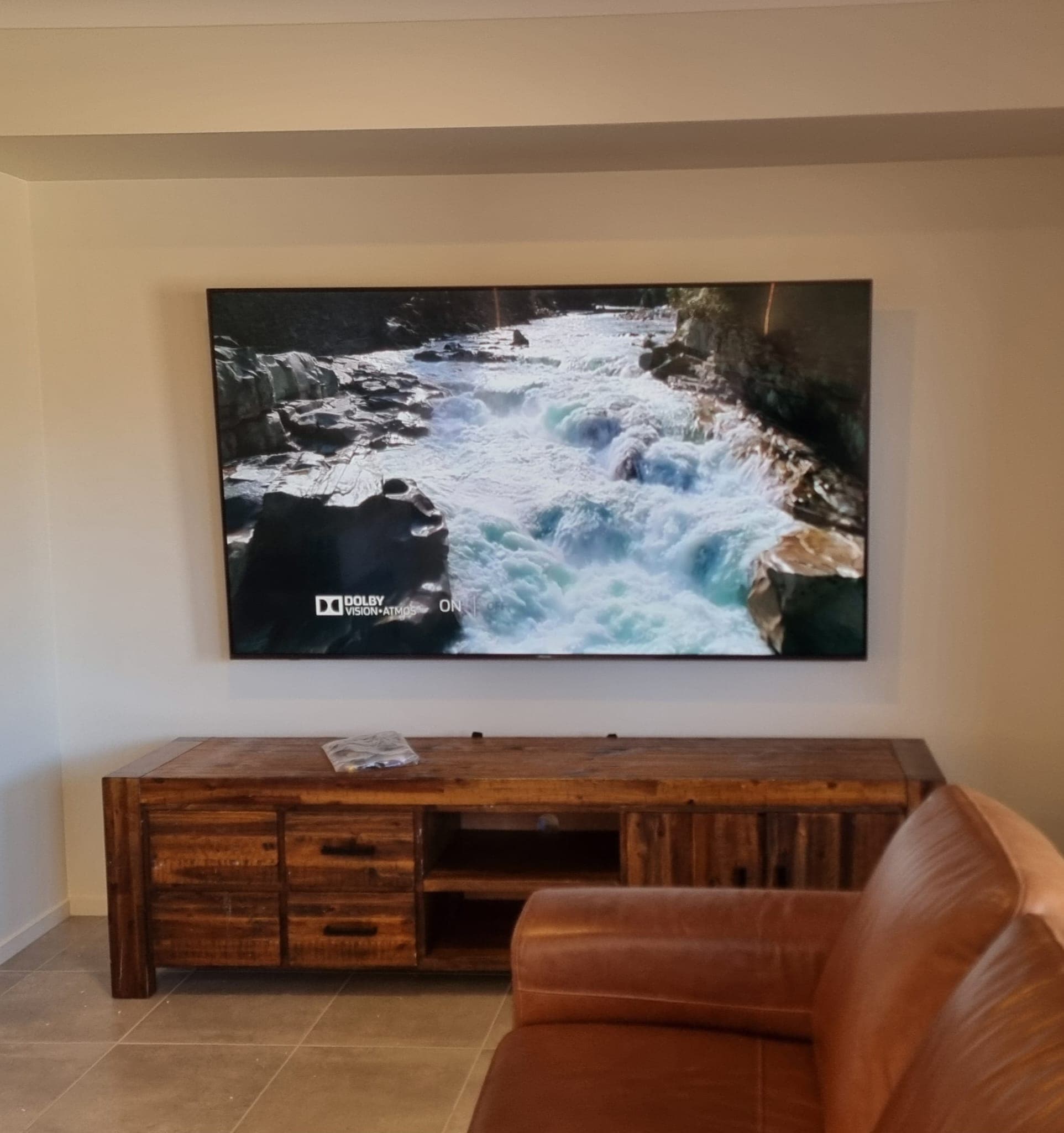 TV showing a waterfall scene above a wooden console